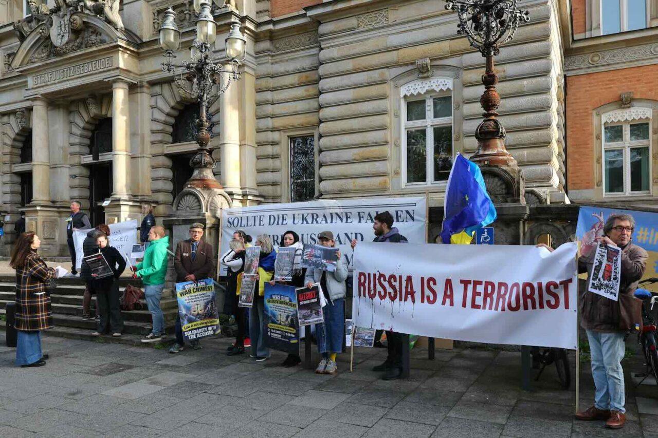demon stranter står utanför en stor stenbyggnad med banderoller framförs sig med texten Russia is terroists